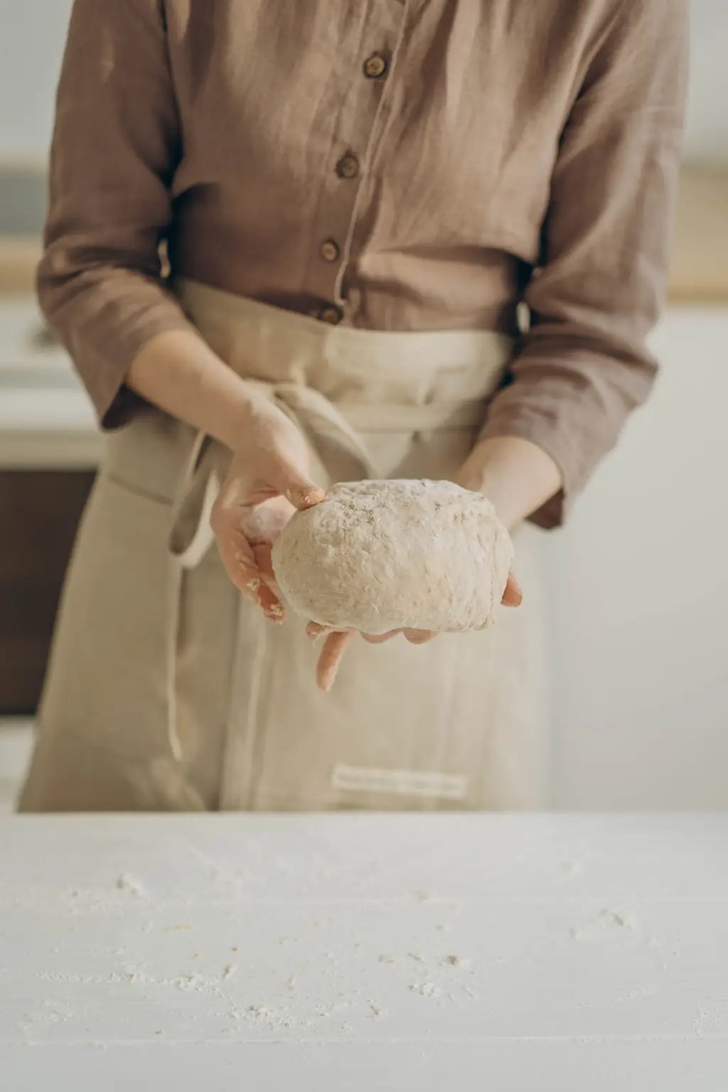 Panadera con delantal sosteniendo una bola de masa