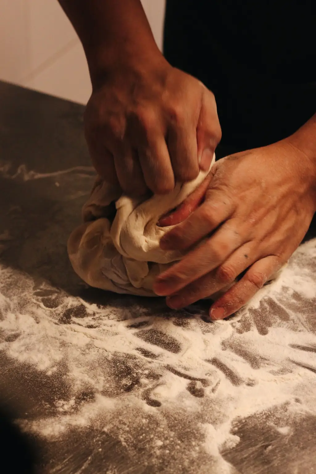 Manos amasando una pieza de pan sobre harina